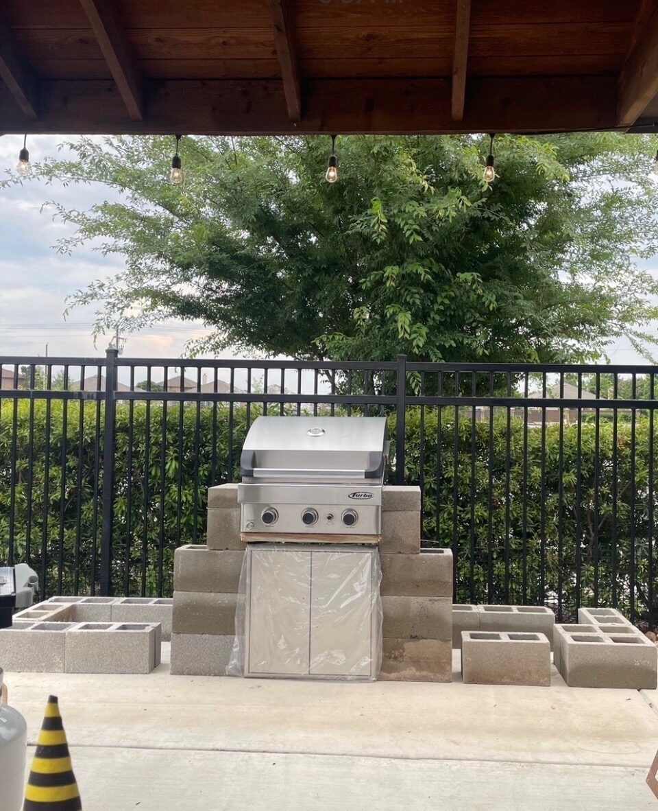 Covered patio and outdoor kitchen enclosed by iron fencing