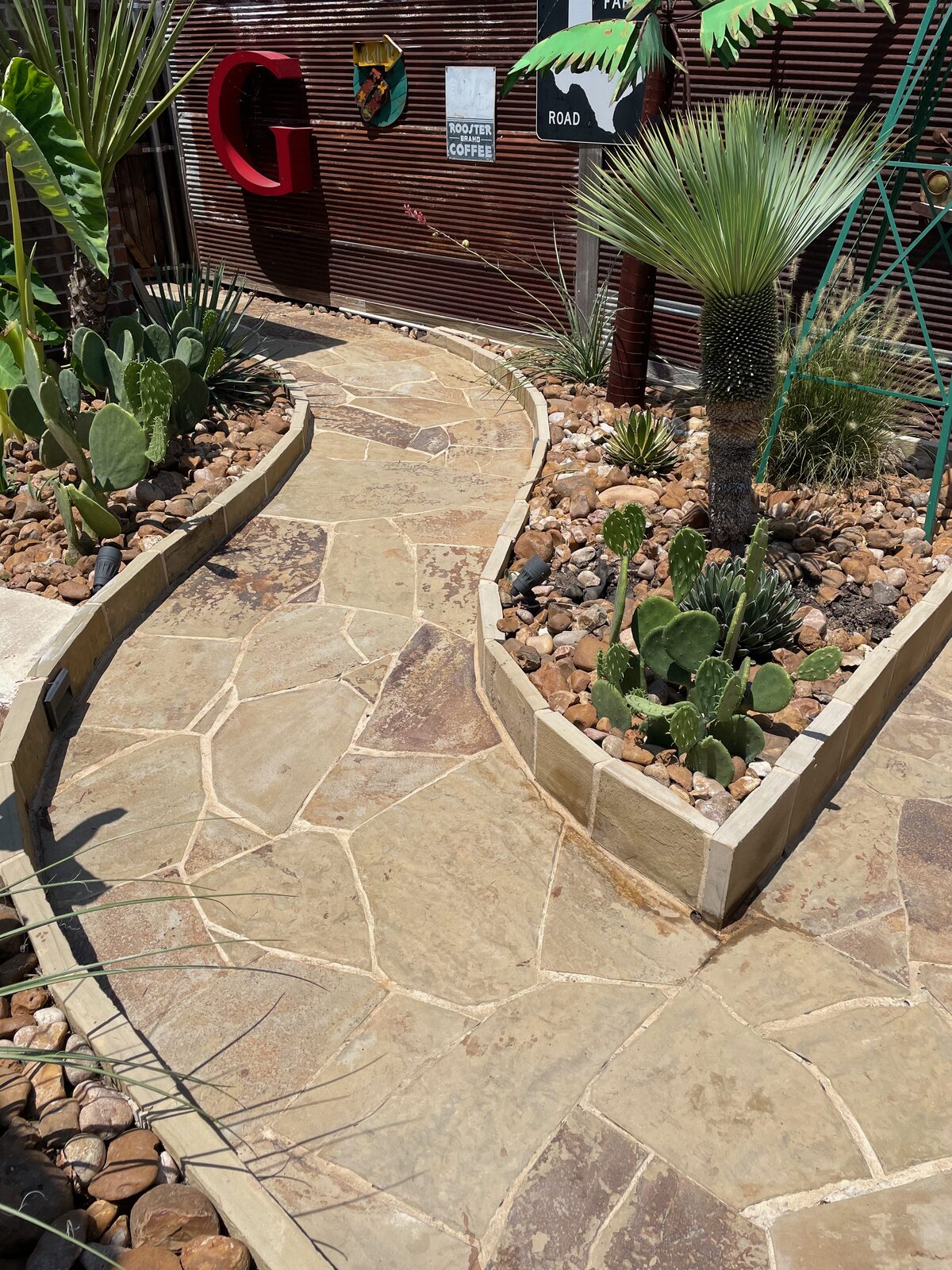 Custom flagstone walkway with stone-bordered desert garden built by Cornerstone Servicing Group